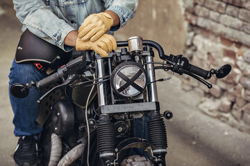 Close up motorcycle detail. Motorcycle front lamp with tape cross over optic. The hands of the...