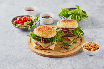Two burgers with veal cutlet and herbs on wooden cutting board