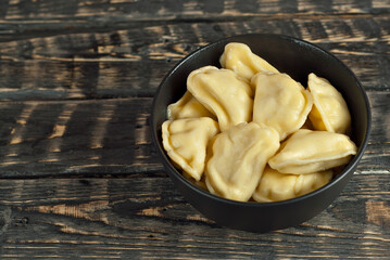 Soldiers in a black bowl. Dough and potato dishes on a black background. Ukrainian national dish on a wooden table. Copy space and free space for text near food.