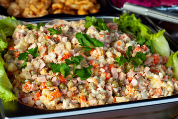 Olivier salad close up. Traditional New Year's Ukrainian dish. Lots of salad in a metal tray.