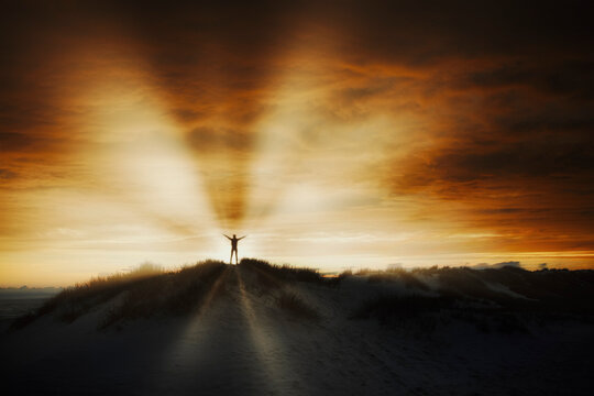 Silhouette of a person standing on a sand dune in a beautiful sunset