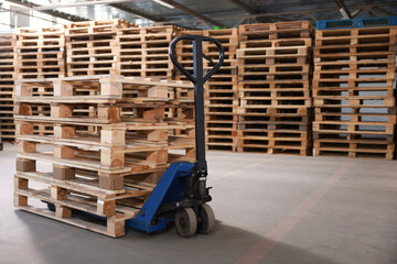 Modern manual forklift with wooden pallets in warehouse, space for text