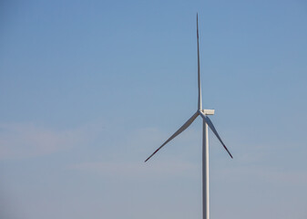 wind mill or also wind-turbine on wind farm in rotation to generate electricity energy on outdoor with sun and blue sky, conservation and sustainable energy concept