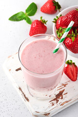 Fruit smoothie. Strawberry smoothie or milkshake with berries and mint in tall glass on light grey background. Summer drink shake, milkshake and refreshment organic concept. Place for text.