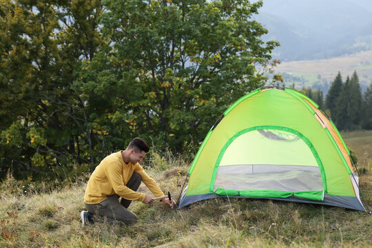 Man Setting Up Camping Tent On Hill