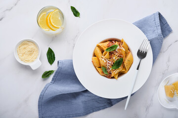 Bolognese Penne Pasta. Tasty appetizing classic italian penne pasta with parmesan cheese, basil and Bolognese sauce in white plate on stone table. Traditional dish of Italian cuisine. Top view.