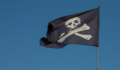 jolly roger. pirate flag.Against the background of blue sky