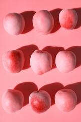 Ripe apricots pattern on pastel pink background. Rose toned, pastel colors background. Healthy fruits. Minimal food and fruit concept. Modern flat lay with hard light and shadow. Pink aesthetic.