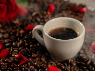 Coffee with smoke, on coffee beans and rose petals with red rose
The concept of congratulations, Valentine's Day, mother's day