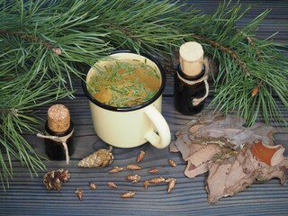 Twigs of pine, cones, pine bark,herbal tea in a mug, oil, tincture extract in bottles on a wooden background, flat layout, top view. Coniferous plant Pinus sylvestris for use in medicine