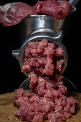Meat in a meat grinder on a black background. Pork meat is twisted in an old meat grinder. meat cooking.