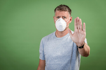 man with ffp2 nose and mouth mask standing in front of green background