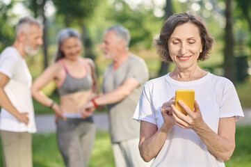 Short-haired woman in a white tshirt with a smartphone