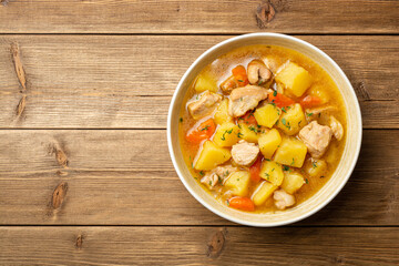 Meat stew with potato and carrot in bowl on wooden background