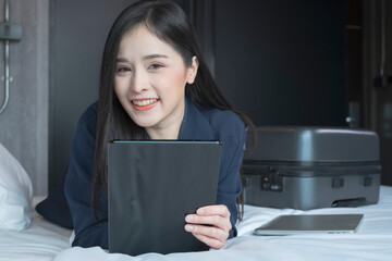 Young businesswoman using tablet working in hotel room during her business travel. Businesswoman working from hotel room on business trip. Female in a hotel room.