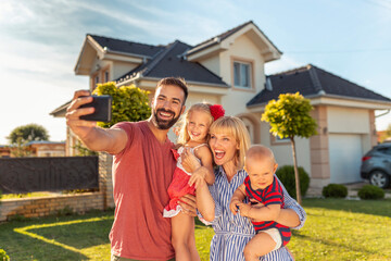 Family taking selfie in front of their new house
