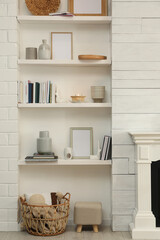 Books, empty frames and different decor on shelves indoors. Interior design