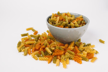 Colored fusilli or rotini variety of pasta formed in corkscrew or helical shapes  in a grey bowl...