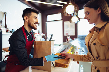 Young woman paying credit card for purchases in grocery store.