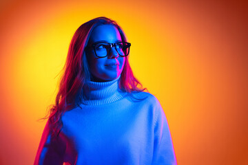 Half-length portrait of young beautiful girl isolated on orange background in neon light, filter. Concept of emotions, facial expression, youth, aspiration, sales - obrazy, fototapety, plakaty