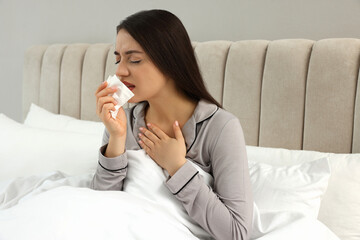 Sick young woman with tissue in bed at home