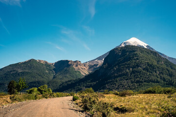 Road to the Top of the volcano peak mountain with snow under the blue sky with grass field and steppes.	