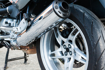 Fototapeta premium The rear wheel of a powerful sports bike with chrome tailpipe.