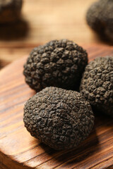 Black truffles with wooden board on table, closeup