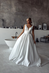 The bride wears a white wedding dress. Wedding preparations. Morning of the bride in the bathroom.