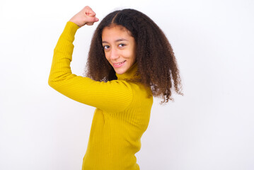 Portrait of powerful cheerful beautiful teenager girl wearing yellow sweater standing against wite...