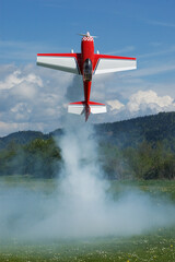 Red and white aerobatic radio controlled airplane hovering vertically