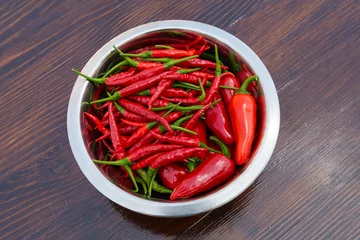Fotobehang Mixed red hot chili peppers in bowl on a wooden table © Robert