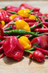Close-up of mixed red, green and yellow hot chili peppers on a wooden table