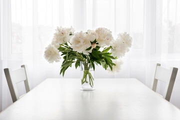 white peonies in a vase  on a white vintage table - copy space