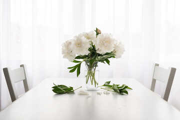 white peonies in a vase and fallen leaves on a white vintage table  - copy space