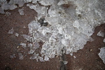 Winter's crystals of ice is in the stream from melt Spring water, flowing on the asphalt.