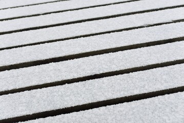 Snow-covered modern wooden pier (jetty, boardwalk) over the frozen river. Ice, frost, snow...