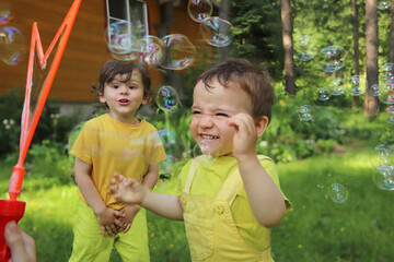 Small children play with soap bubbles in the summer outdoors.