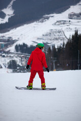 Fototapeta na wymiar A man in a red jacket with a snowboard stands on a mountainside.