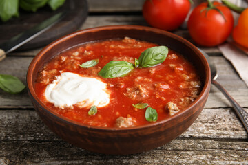 Bowl of delicious stuffed pepper soup on wooden table, closeup
