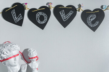 Festive background for Valentine's Day with black hearts with the inscription Love, male and female bust with a red ribbon on the eyes on a white background. Layout with copy space for design.