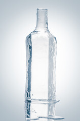 Bottle form sculpture, made of pure transparent ice. Melting on a reflective surface.