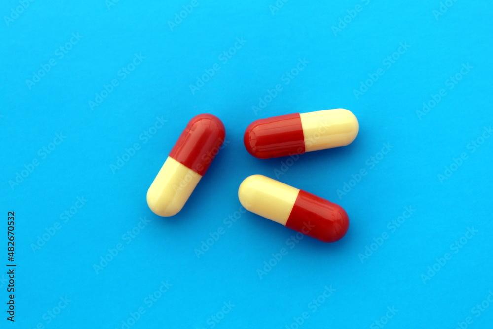 Wall mural Three medicines in a capsule lies on a blue background