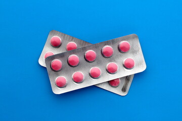 Two plates of pink pills lie on a blue background.