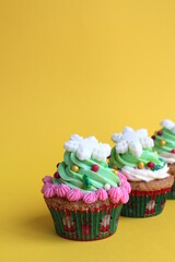 A cupcake with a lot of cream and decorated with a snowflake stands on a yellow background.