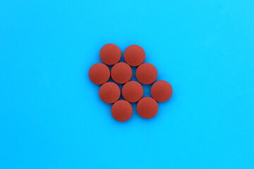 On a blue background lies a pile of brown pills.