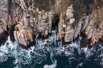 Aerial view of waves crash to the cliffs