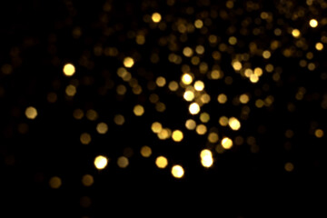 Golden blurred bokeh lights on black background. Glitter sparkle stars for celebrate. Overlay for your design