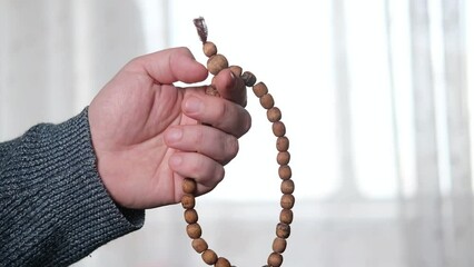 Rosary in a man's hand close-up. Prayer, meditation concept.
