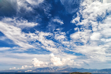White clouds on blue sky or azure sky background, over mountain ranges. Landscape